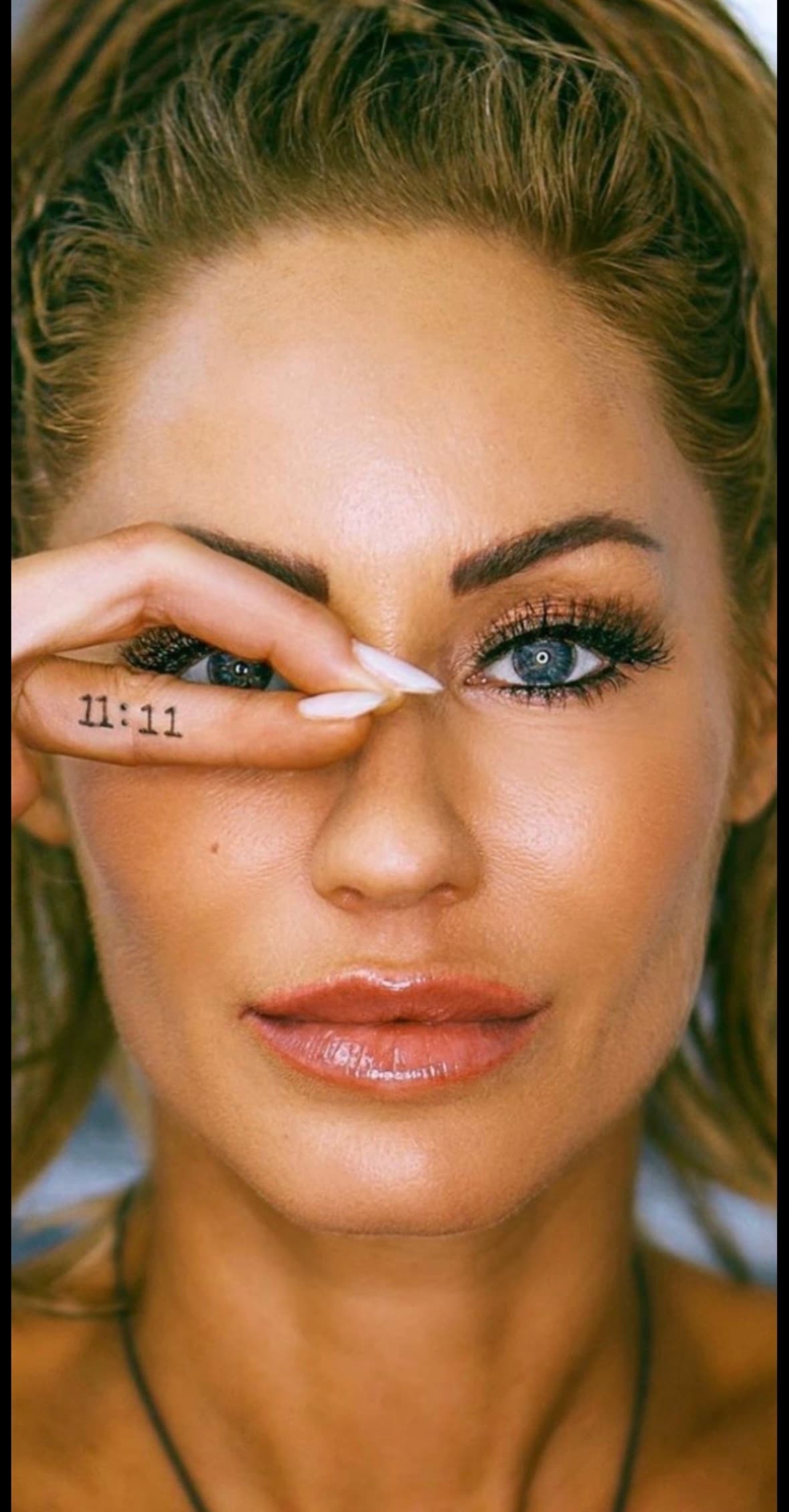 Melanie Marden with her 11:11 tattoo, one hand over an eye