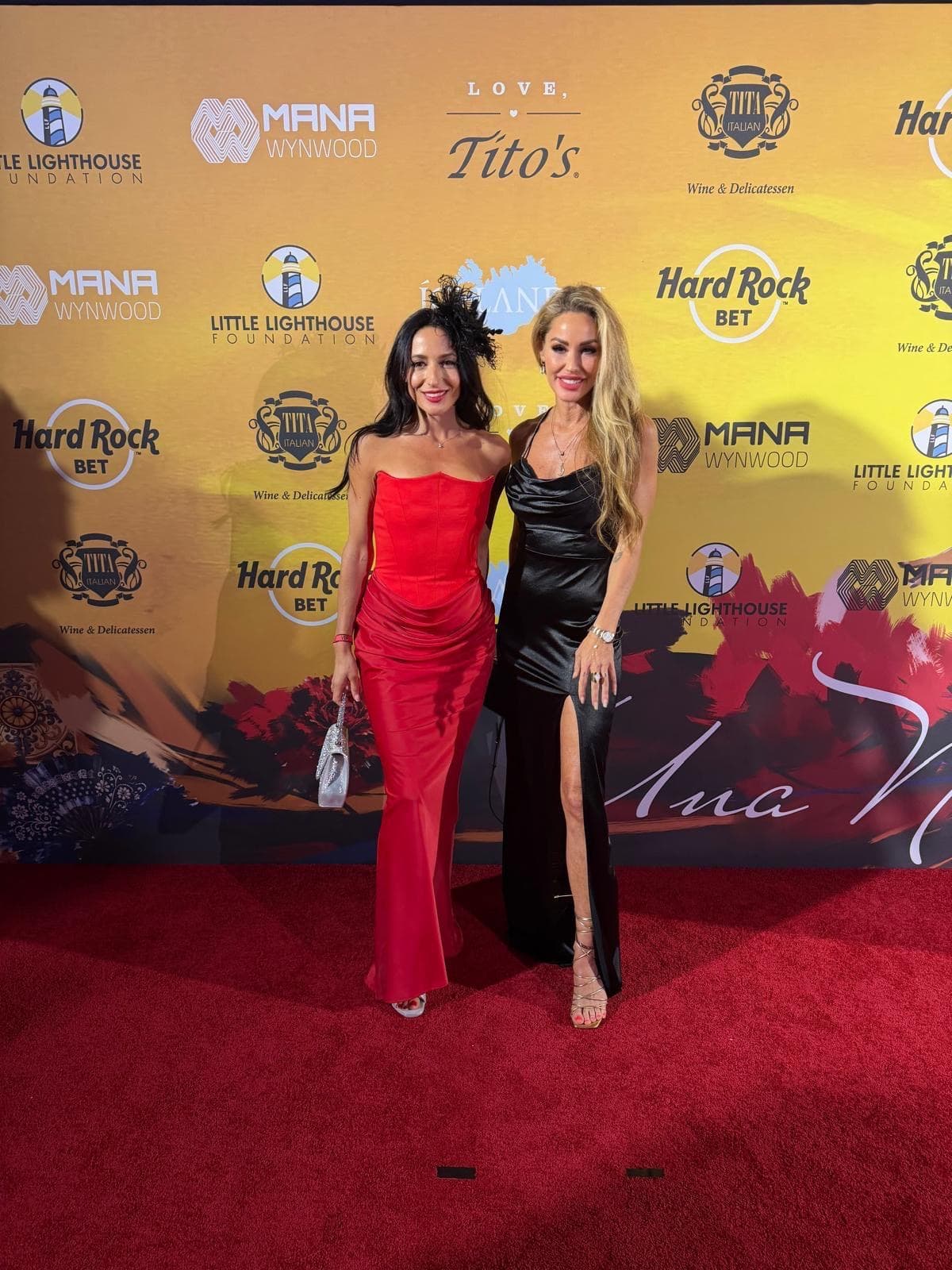 Melanie Marden in a black gown with a friend in red on a red carpet