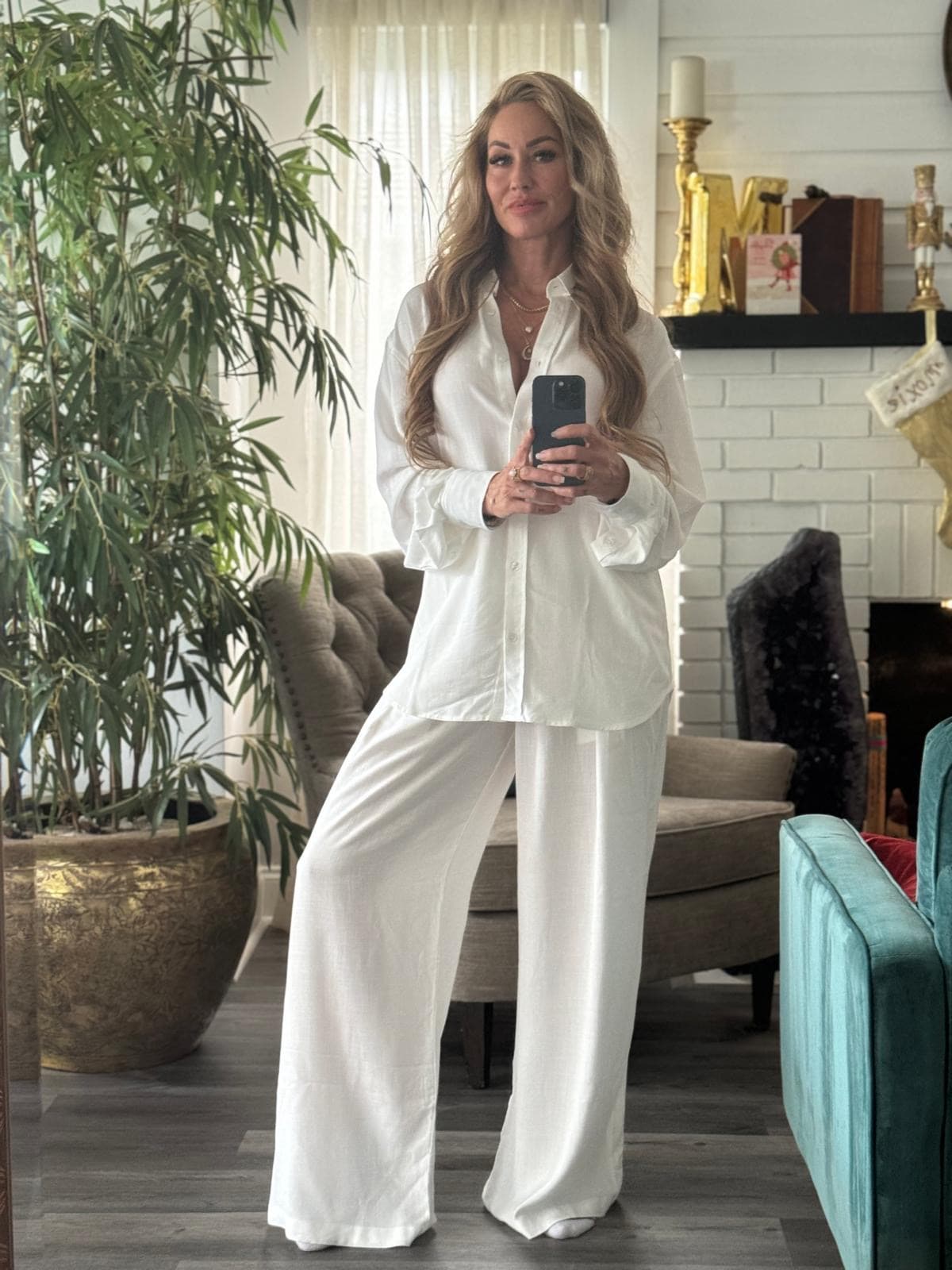 Melanie Marden in a white shirt and trousers, photographed in a mirror at home