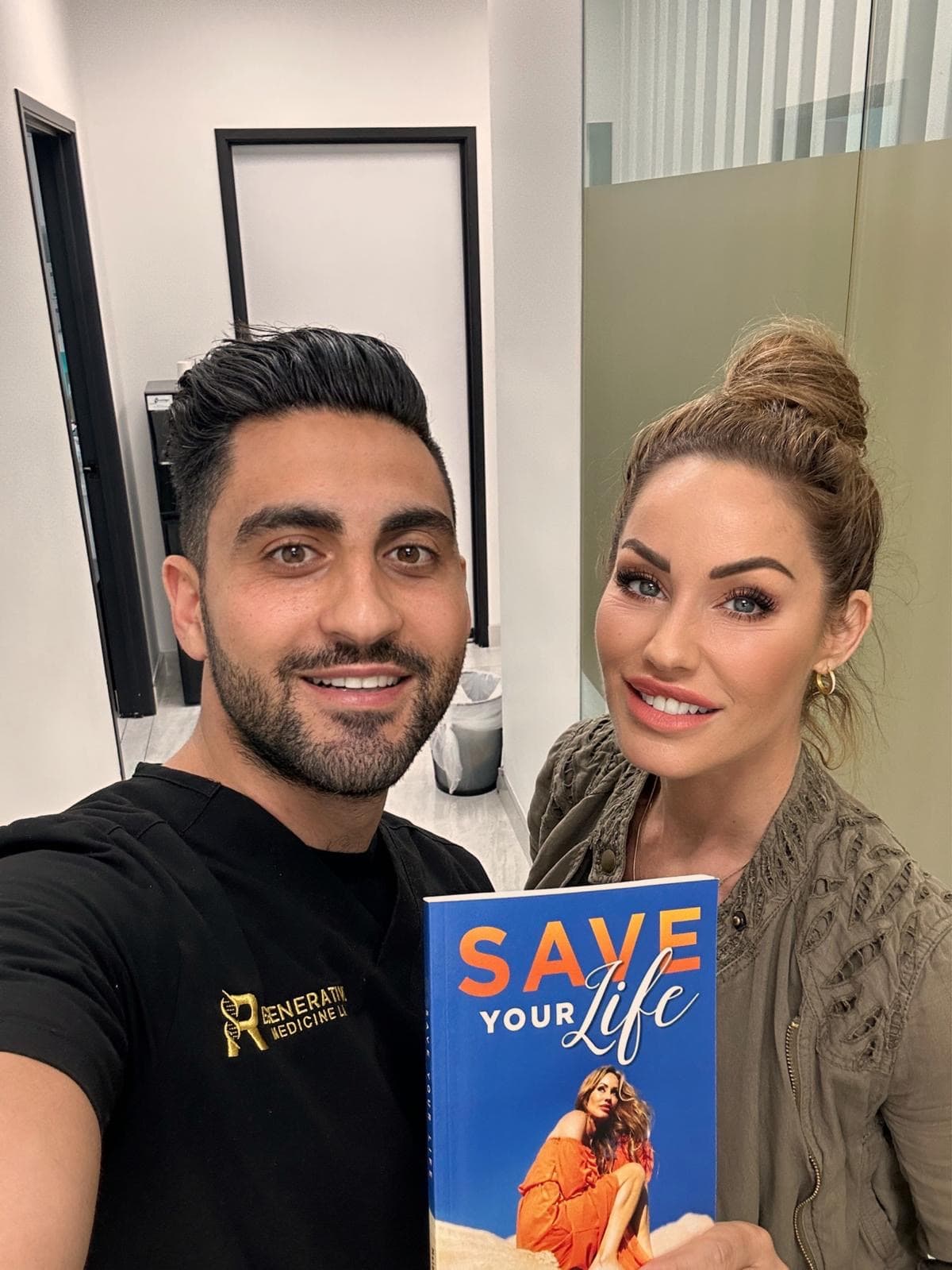 Melanie Marden with Dr. Mark Ghalili, in a Regenerative Medicine shirt, holding a copy of Save Your Life